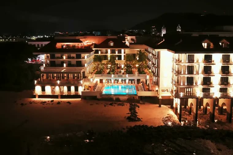 A hotel lit up at night beside its pool
